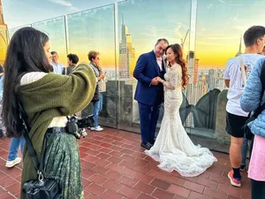 An engaged couple takes photos at Top of the Rock in NYC's Rockefeller Center.